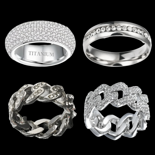 A set of four silver-colored rings with varying designs, including a pave-set ring, a chain-link ring, a sleek band ring, and a wide-band detailed ring.