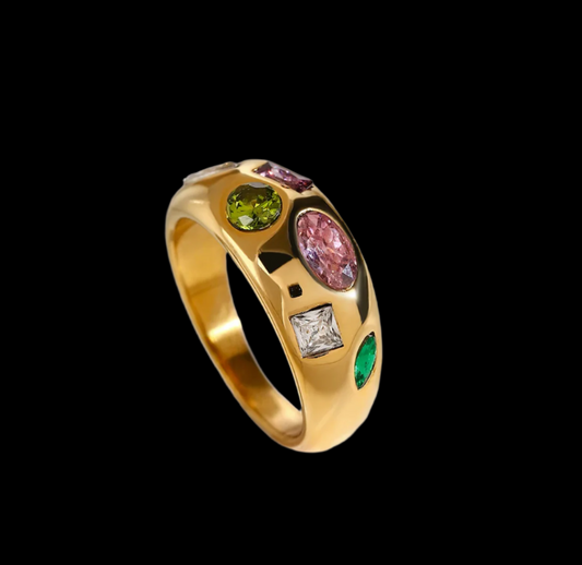 Gold ring with colorful gemstones on a textured white surface