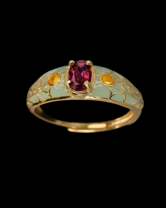 Gold ring with a red gemstone and green enamel on a black background